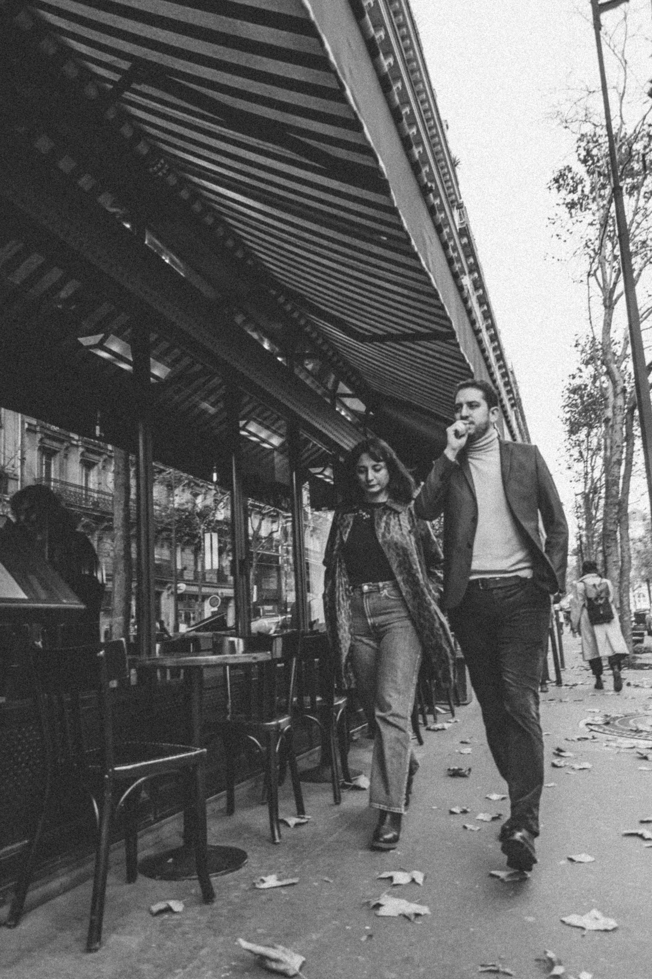 A couple walking past a Parisian café
